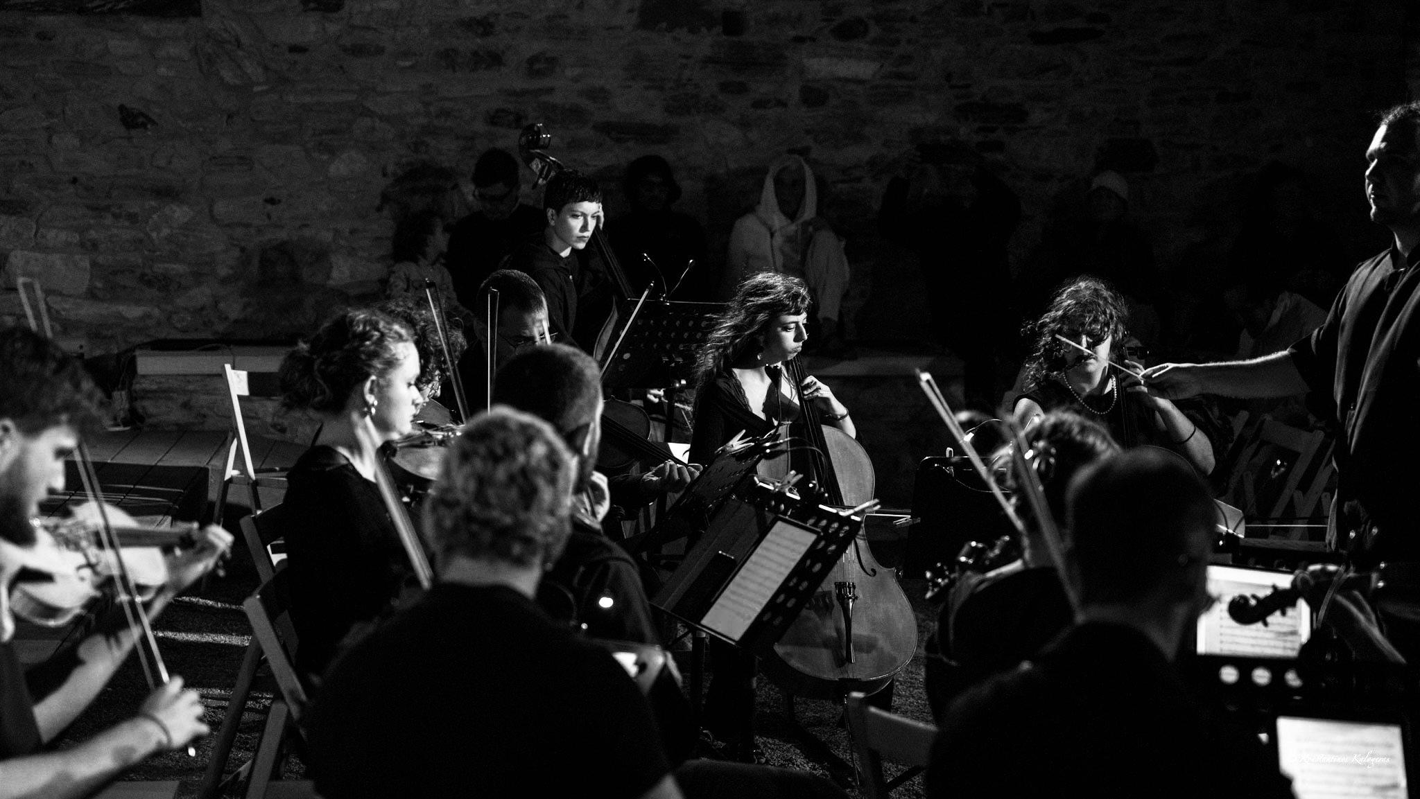 String players performing outdoors at night against an old stone wall.