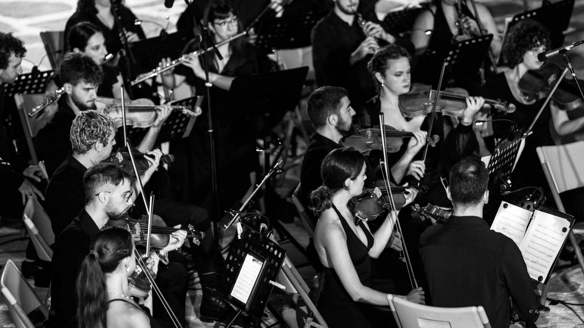 A large string section seen from above, reading from tablets on their stands.